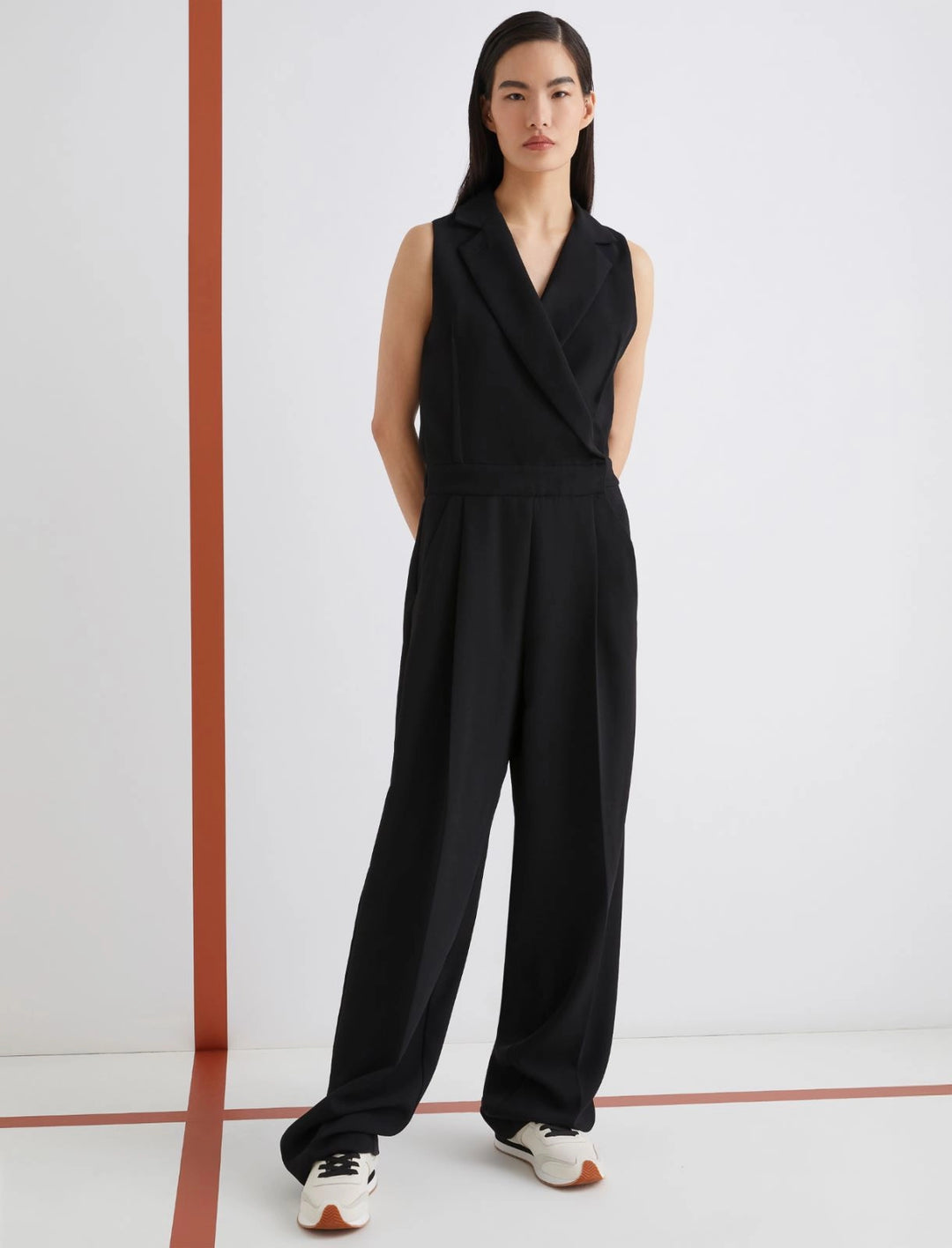 Person wearing a black sleeveless jumpsuit on a white background
