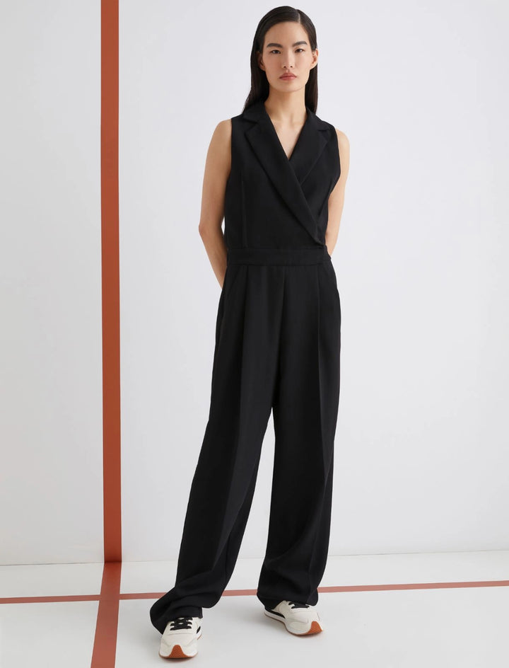 Person wearing a black sleeveless jumpsuit on a white background