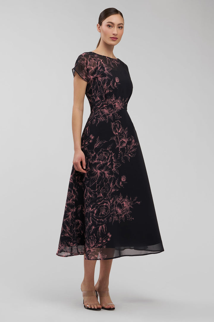 Woman wearing a black dress with pink floral pattern on a white background