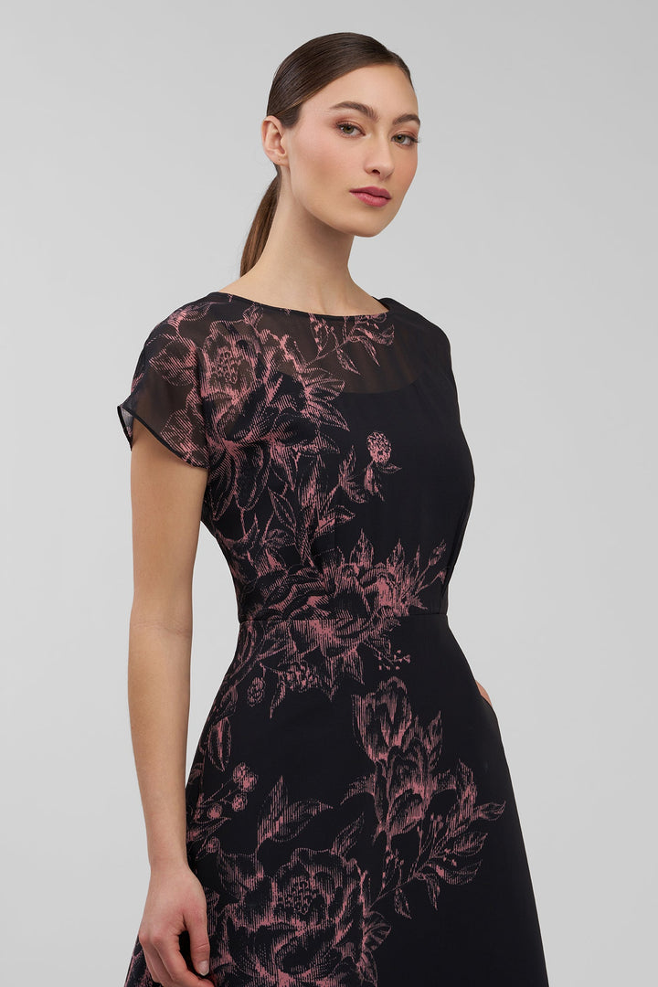 Woman wearing a black dress with pink floral patterns on a gray background