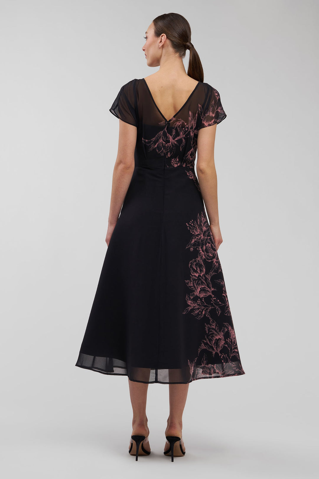 Woman wearing a black dress with floral patterns on a white background