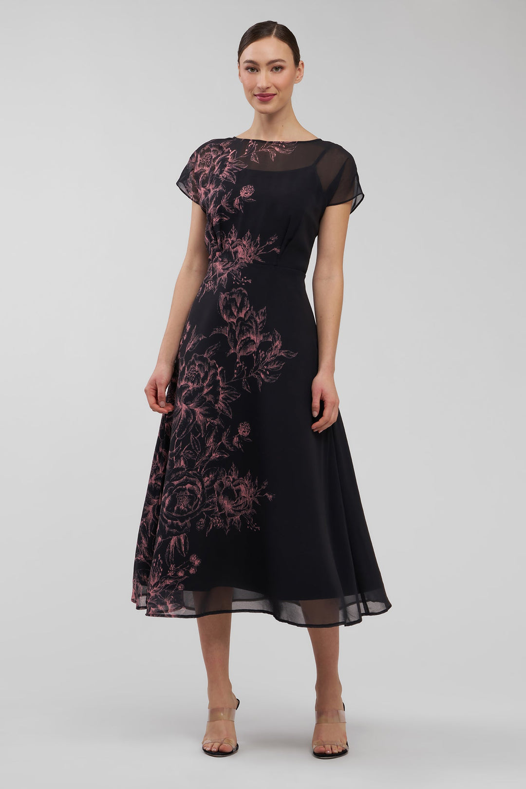Woman wearing a black dress with pink floral patterns on a white background